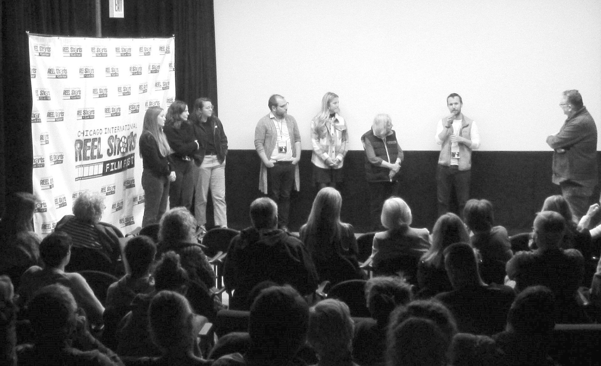 Panel of people on a stage, facing an audience at a film screening.