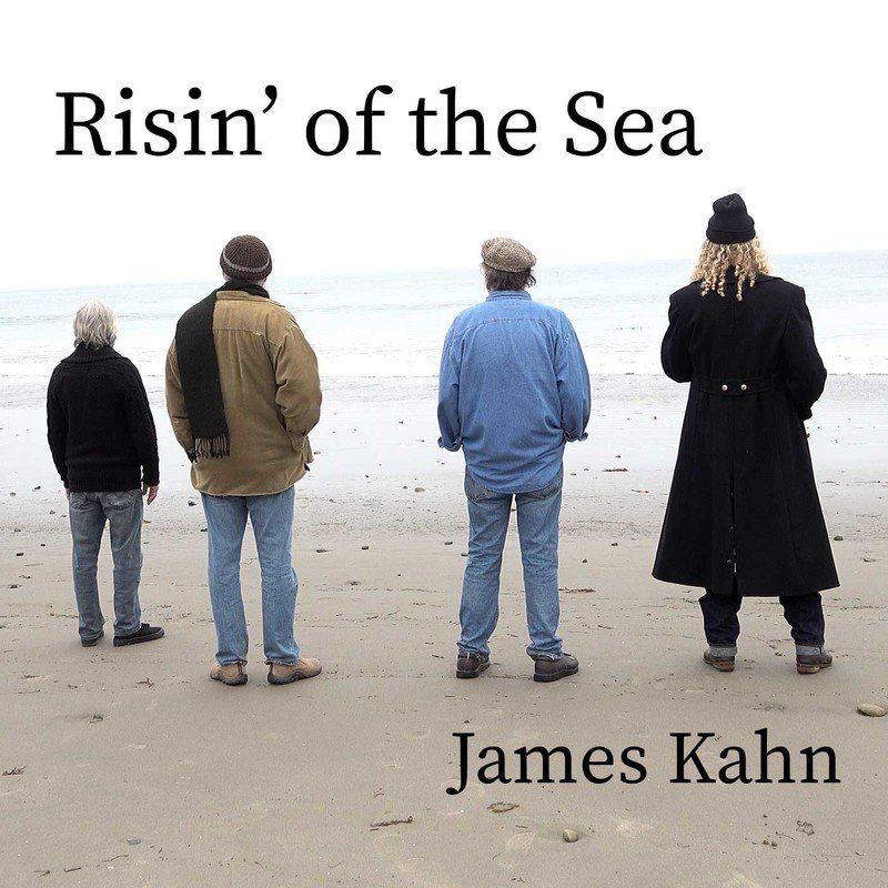 Four people stand on a beach, facing the sea. Album cover: