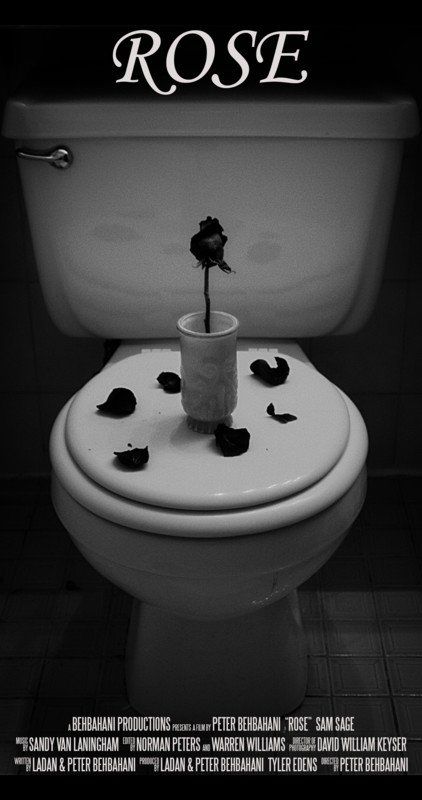 Black and white photo of a rose in a glass on a toilet seat, petals scattered. The word