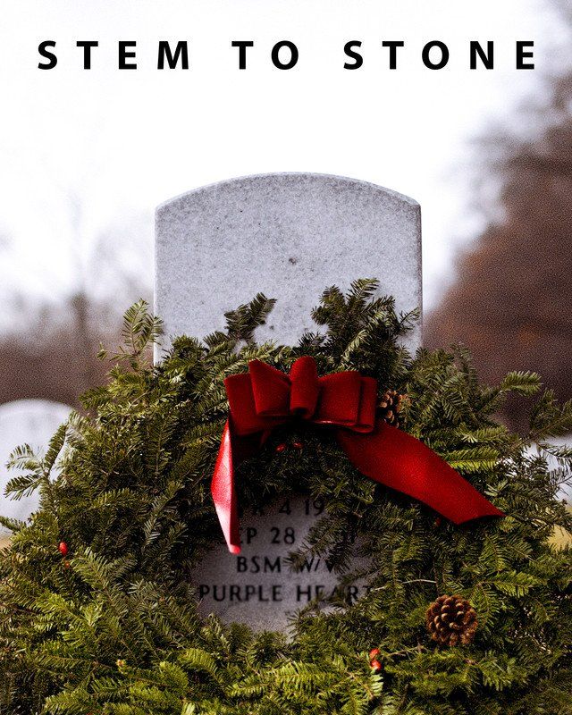Gravestone with evergreen wreath and red bow;