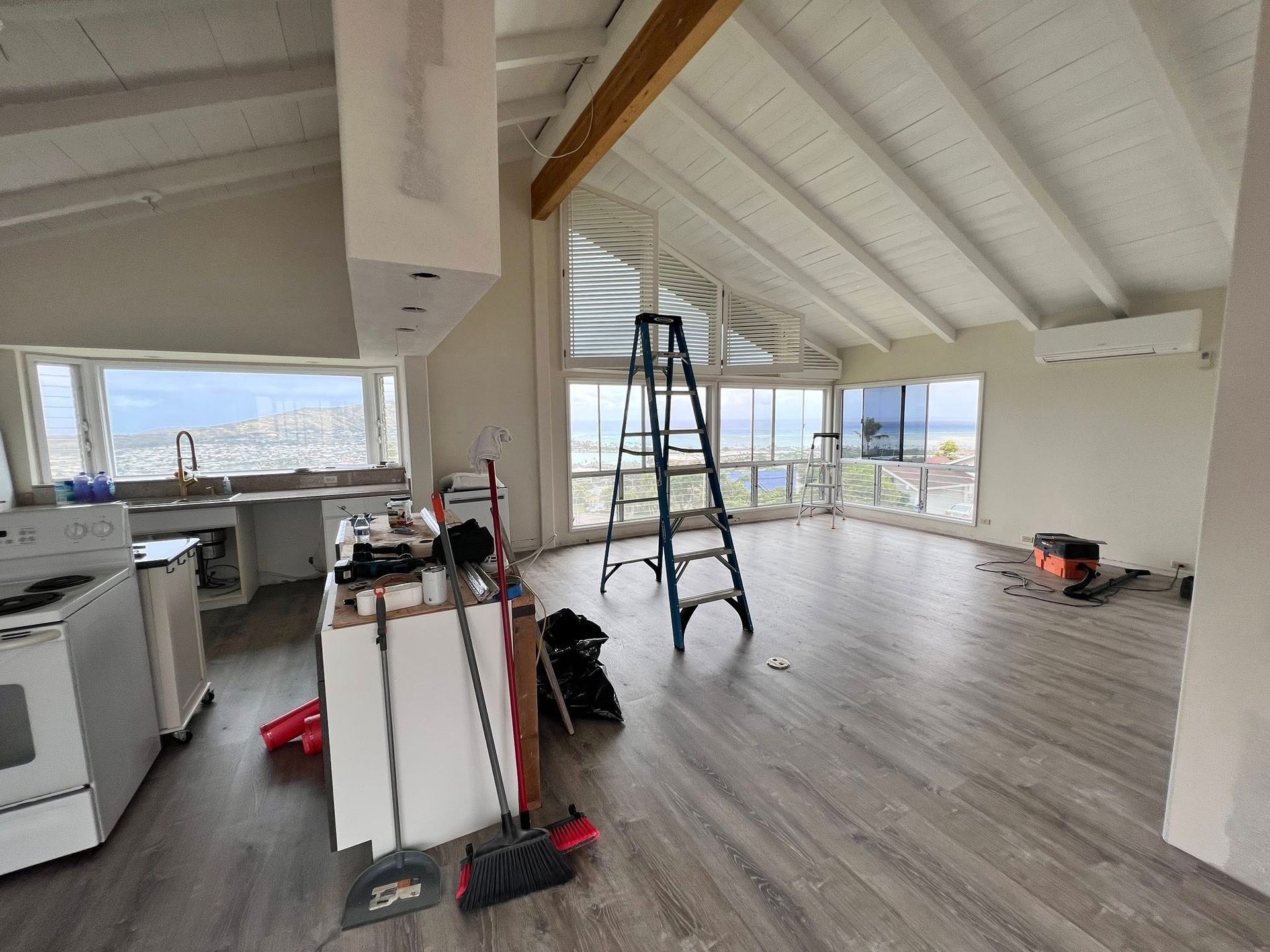 Interior of a home under construction with kitchen, ladder, and large windows with a view.