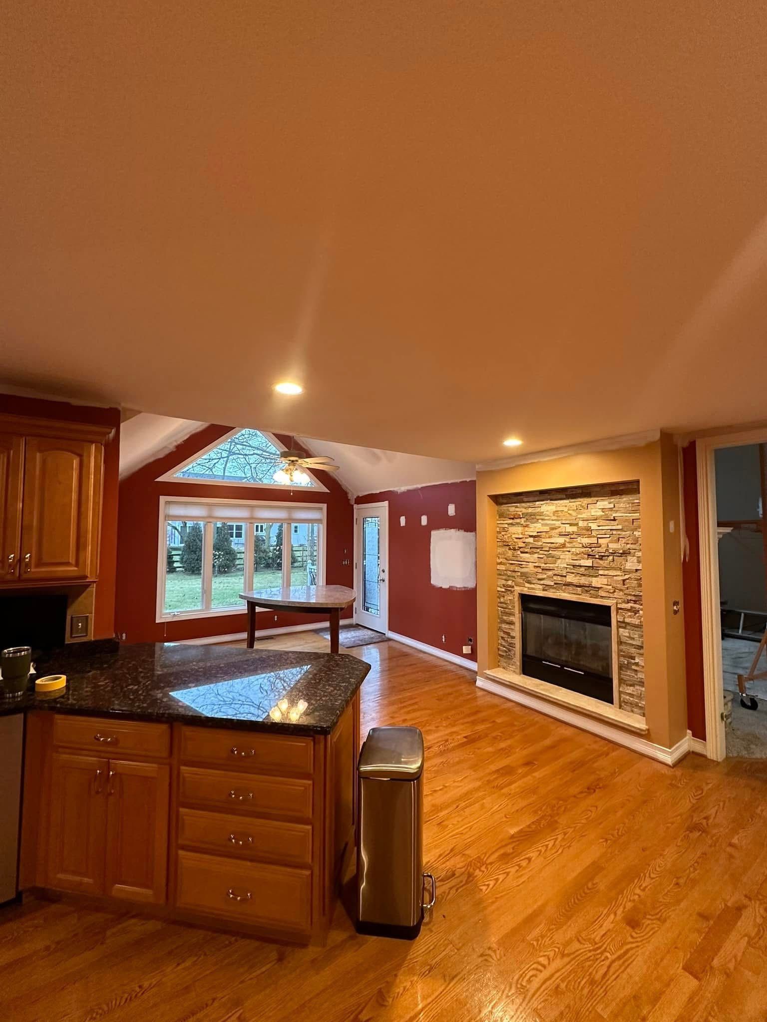 Kitchen and living room with fireplace, wood floors, and cabinetry; red and beige walls.