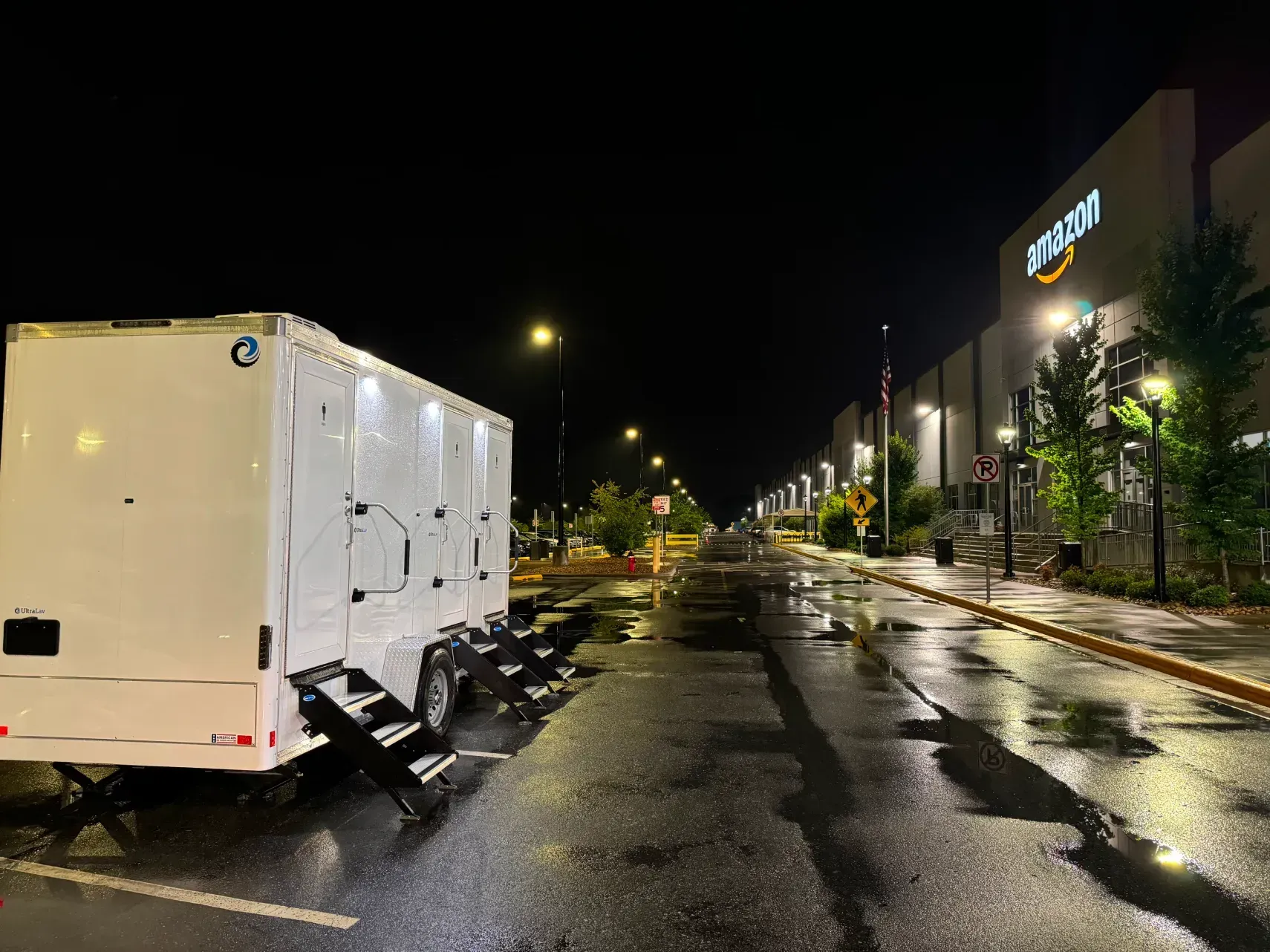 White truck parked on a wet night street beside a lit industrial building