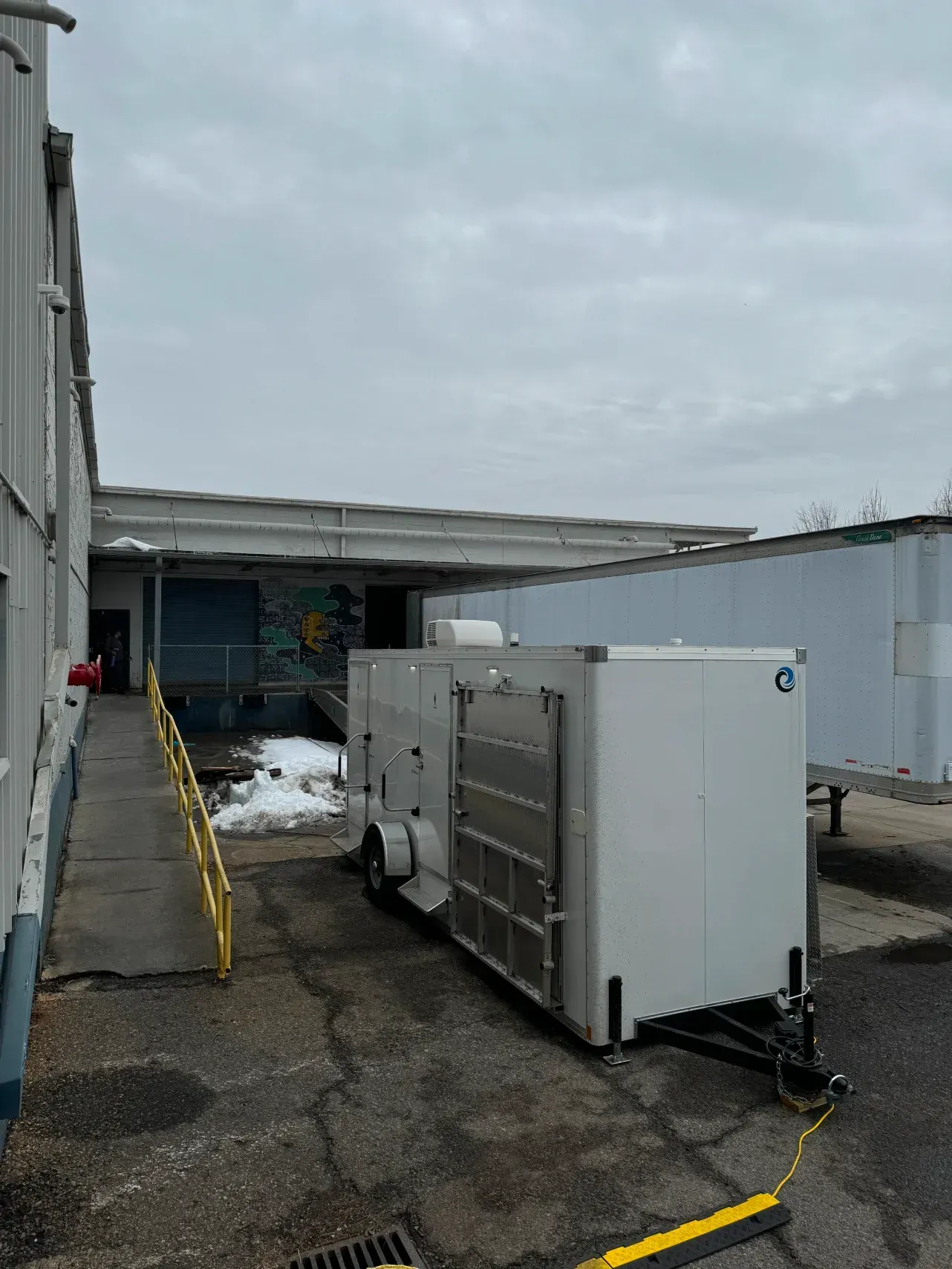Industrial rooftop with HVAC units and ductwork beside a building under an overcast sky