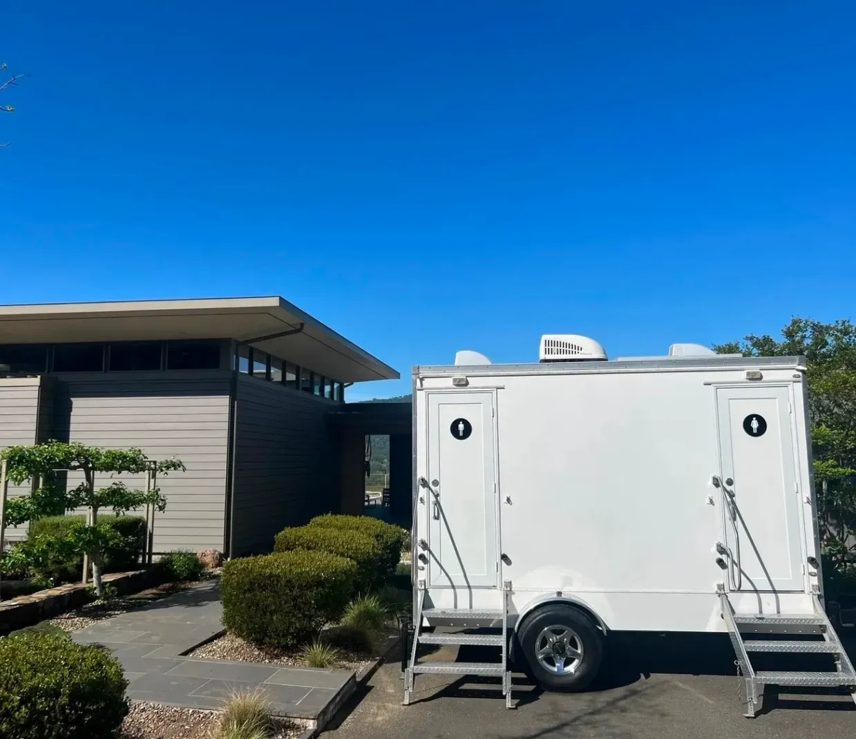 White trailer parked beside a building under a clear blue sky.