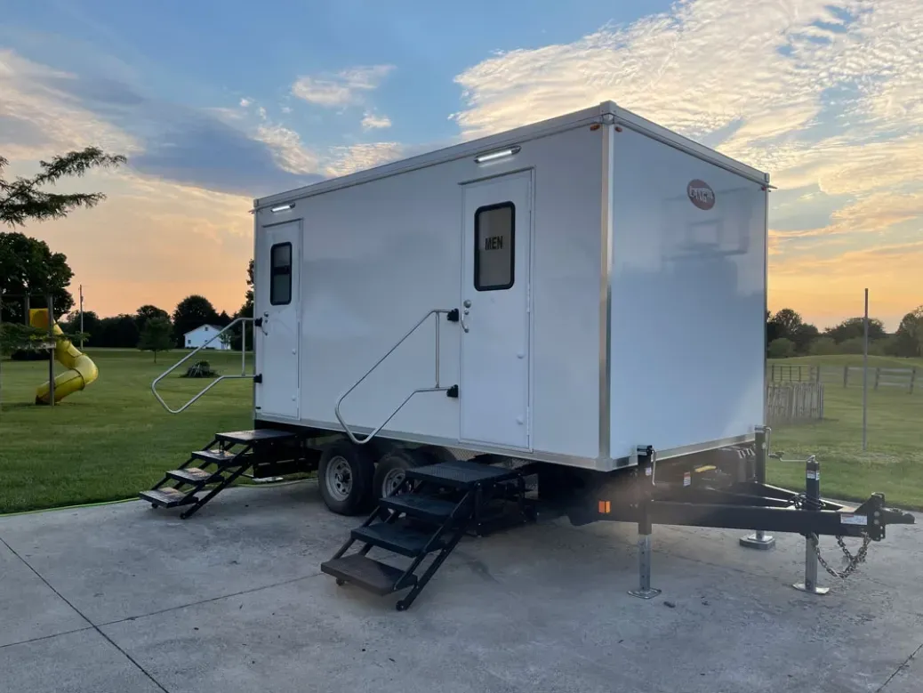 White mobile tiny house on a trailer with steps, parked on a concrete pad at sunset