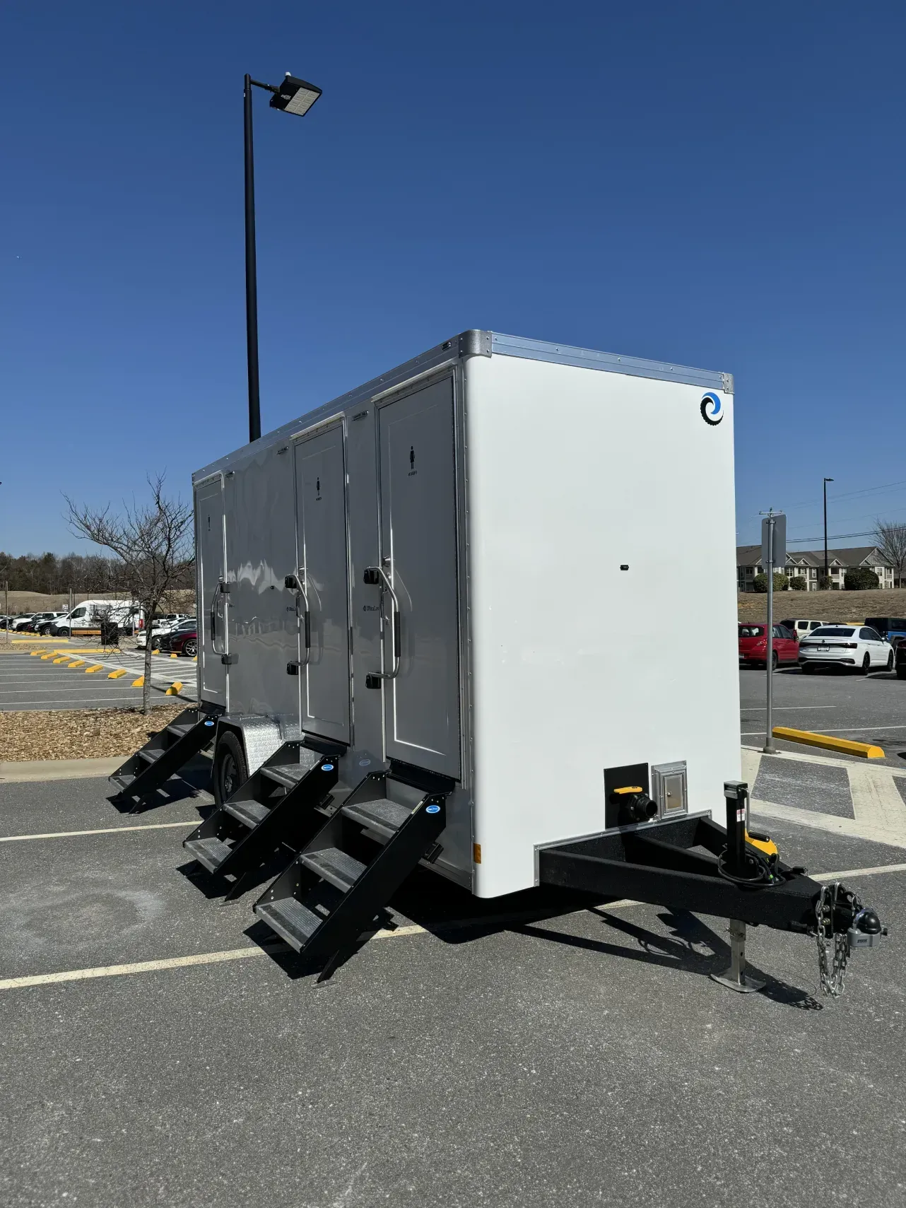 White trailer with ramps parked in a lot under a clear blue sky.