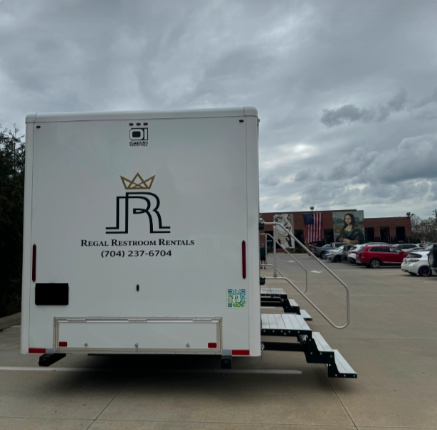 White rental trailer with “Royal Rentals” logo parked on a cloudy street near a ramp and other vehicles
