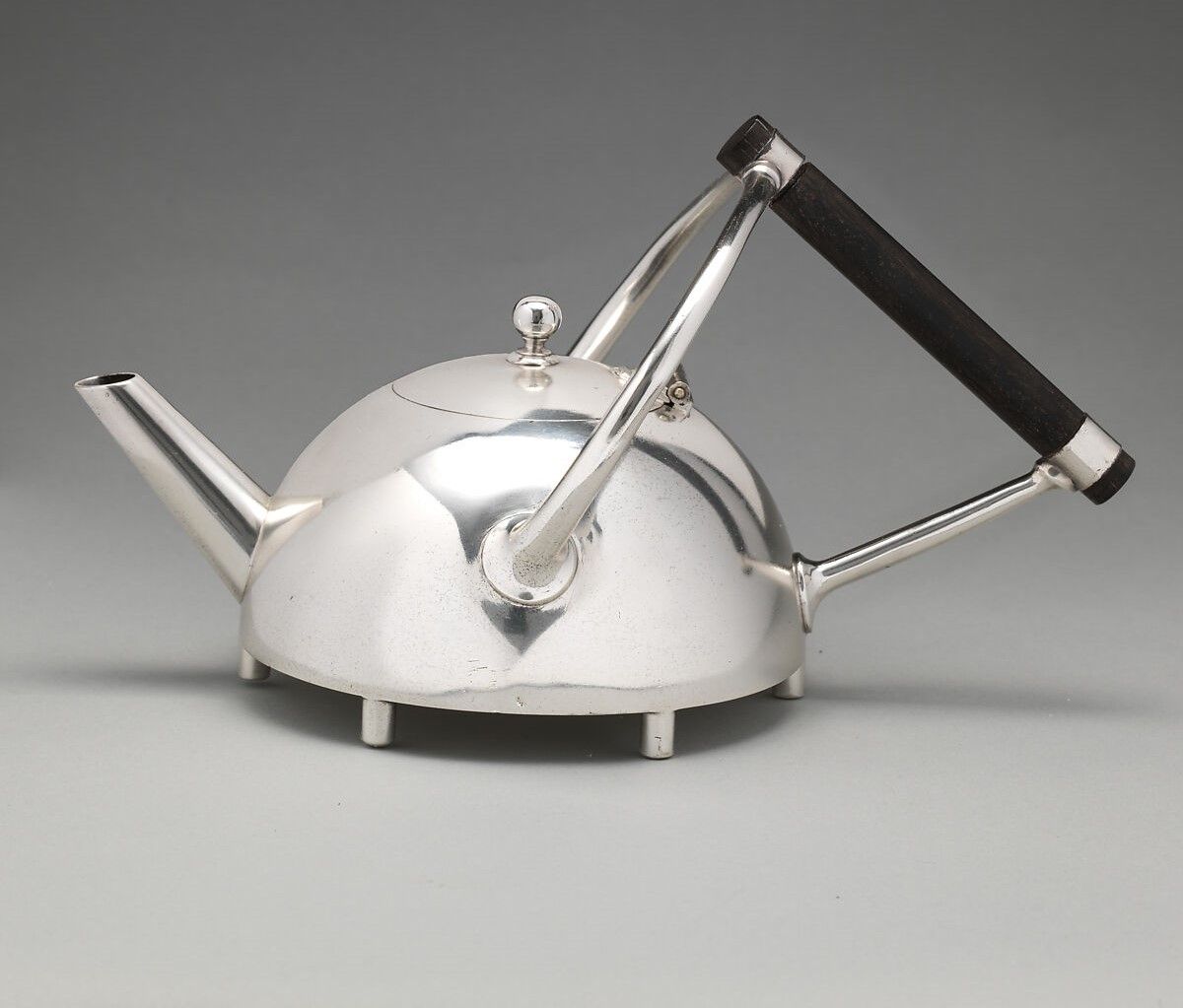 Quastel Associates Valuers | Silver teapot with a black handle, sitting on a gray background.