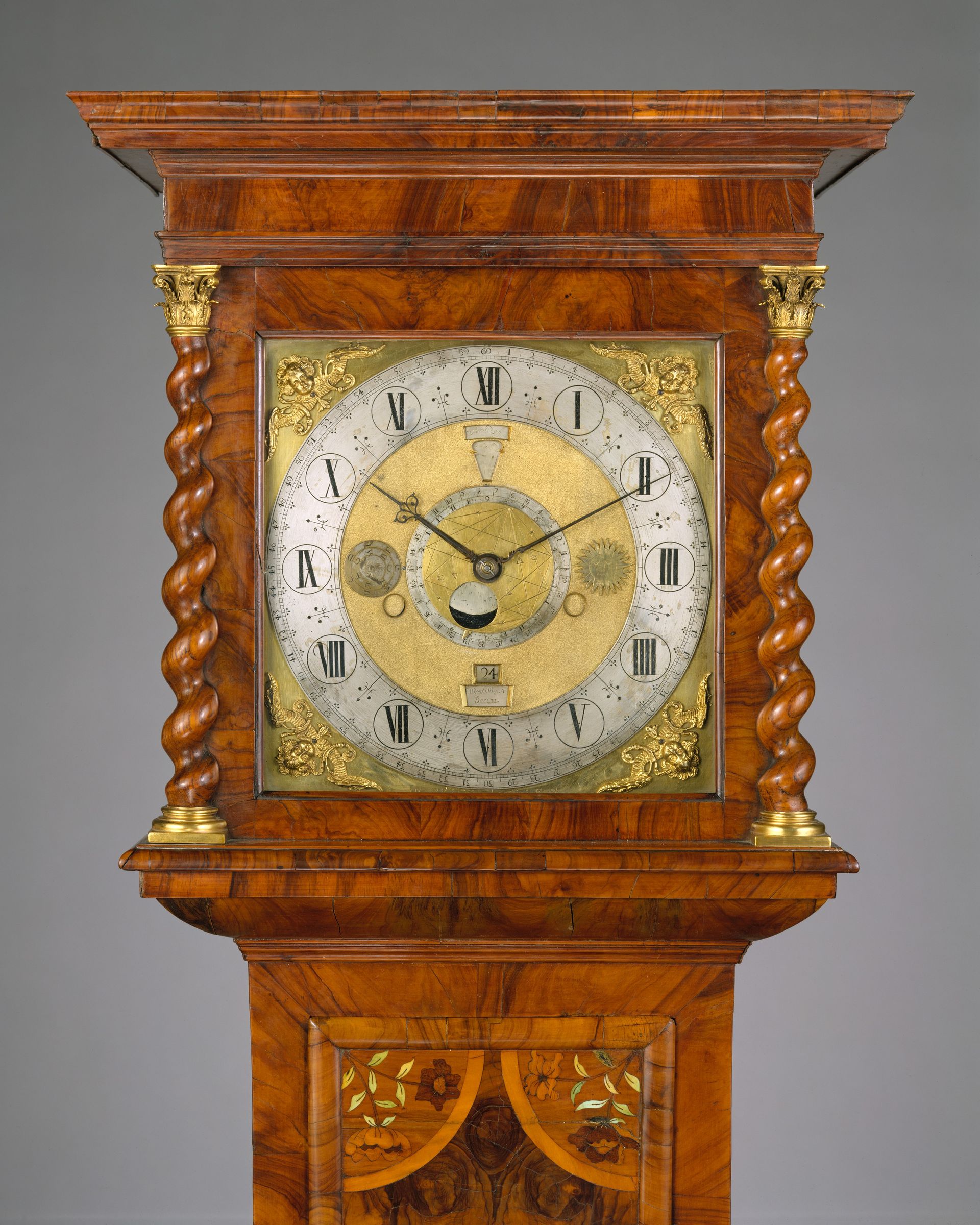 Quastel Associates Valuers | Close-up of a tall, ornate wooden grandfather clock with a gold and silver face.
