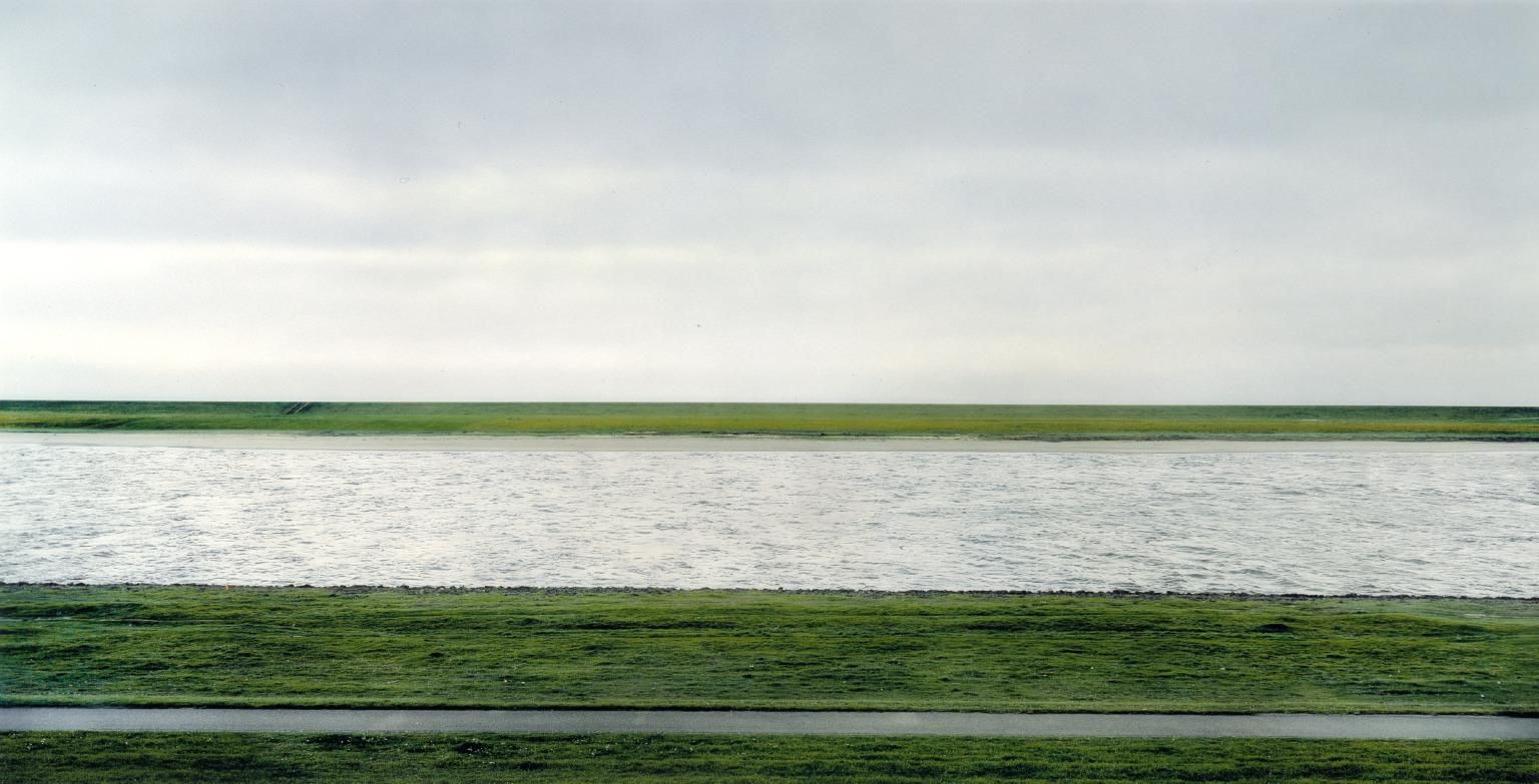 Quastel Associates Valuers | A vast expanse of water, green embankments, and a grey sky.