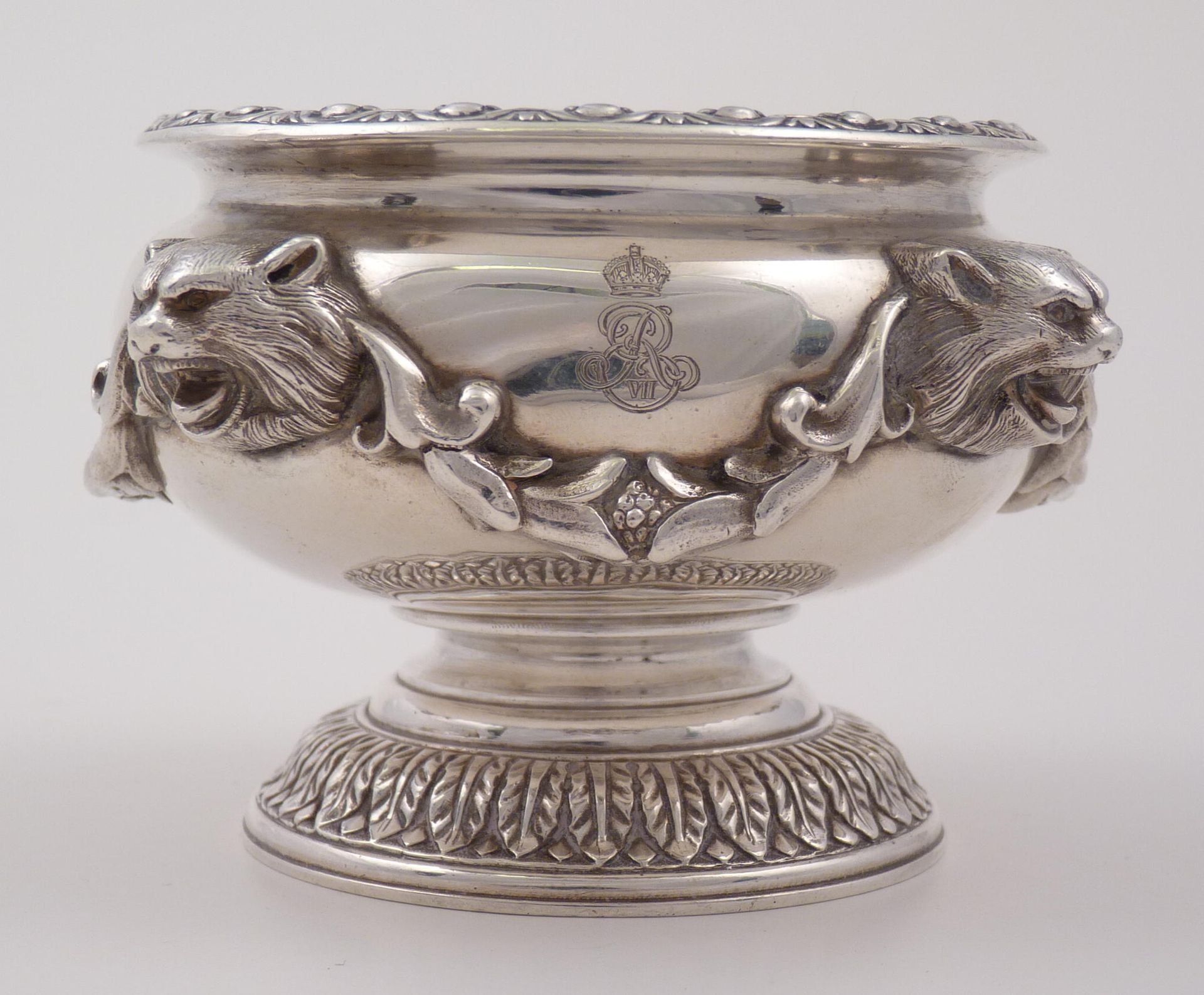 Quastel Associates Valuations | Silver bowl with lion heads, decorative elements, and a crest.