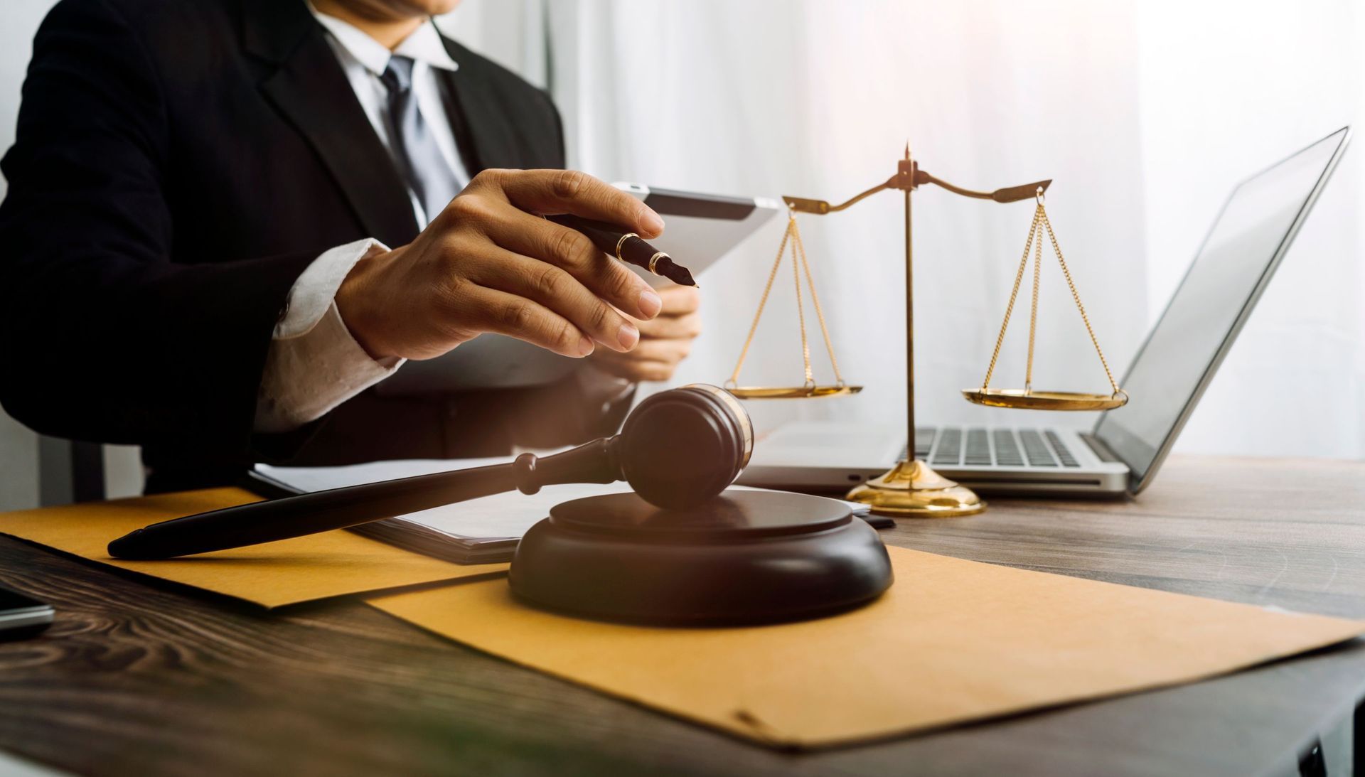 Lawyer at desk with gavel, scales of justice, laptop.