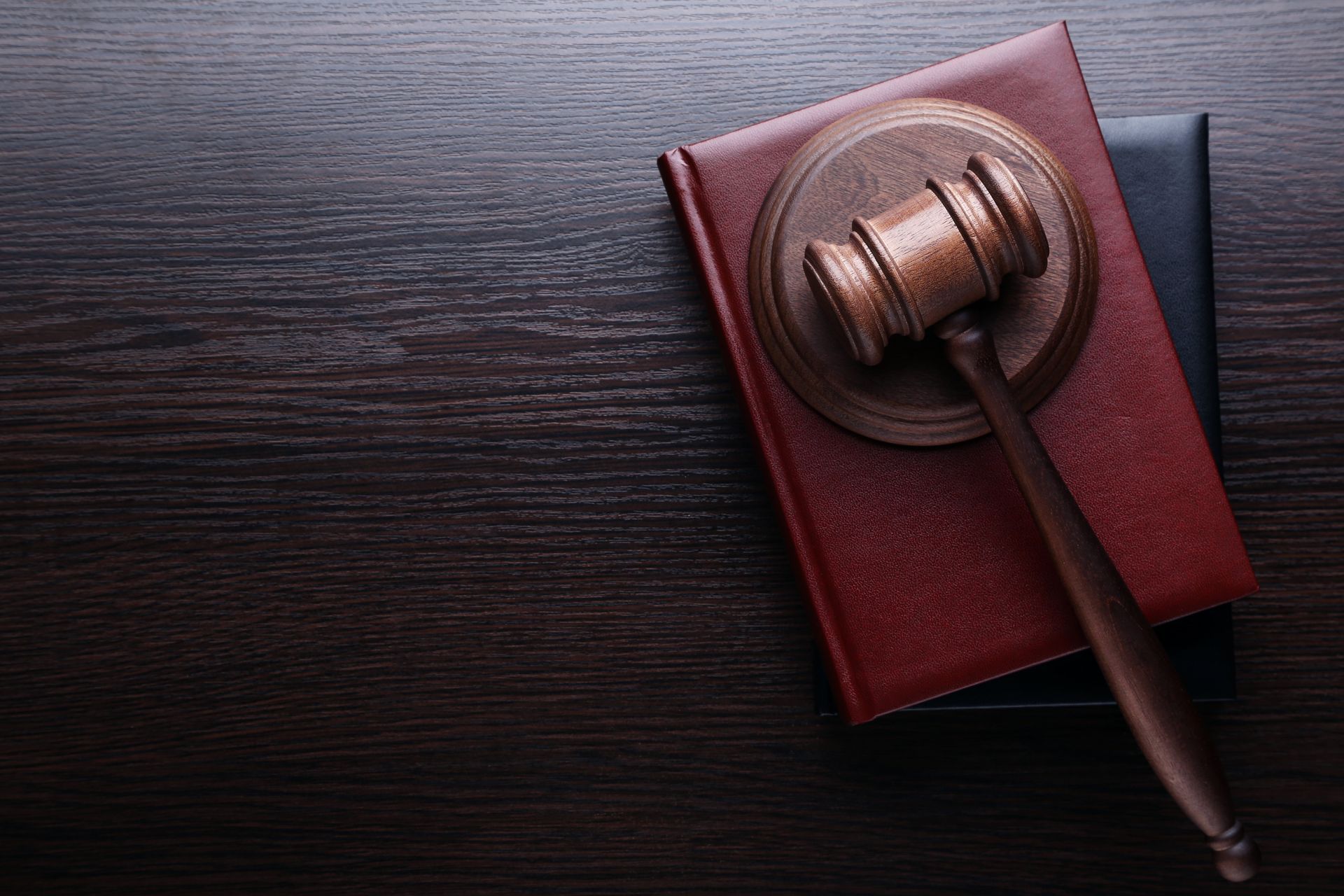 Gavel resting on top of two law books on a dark wooden surface.