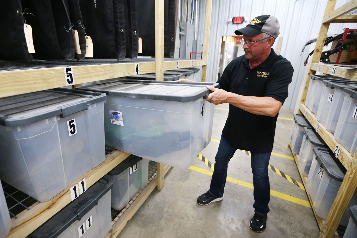 Expert staff looking through bins in storage space | Windham Bodyshop