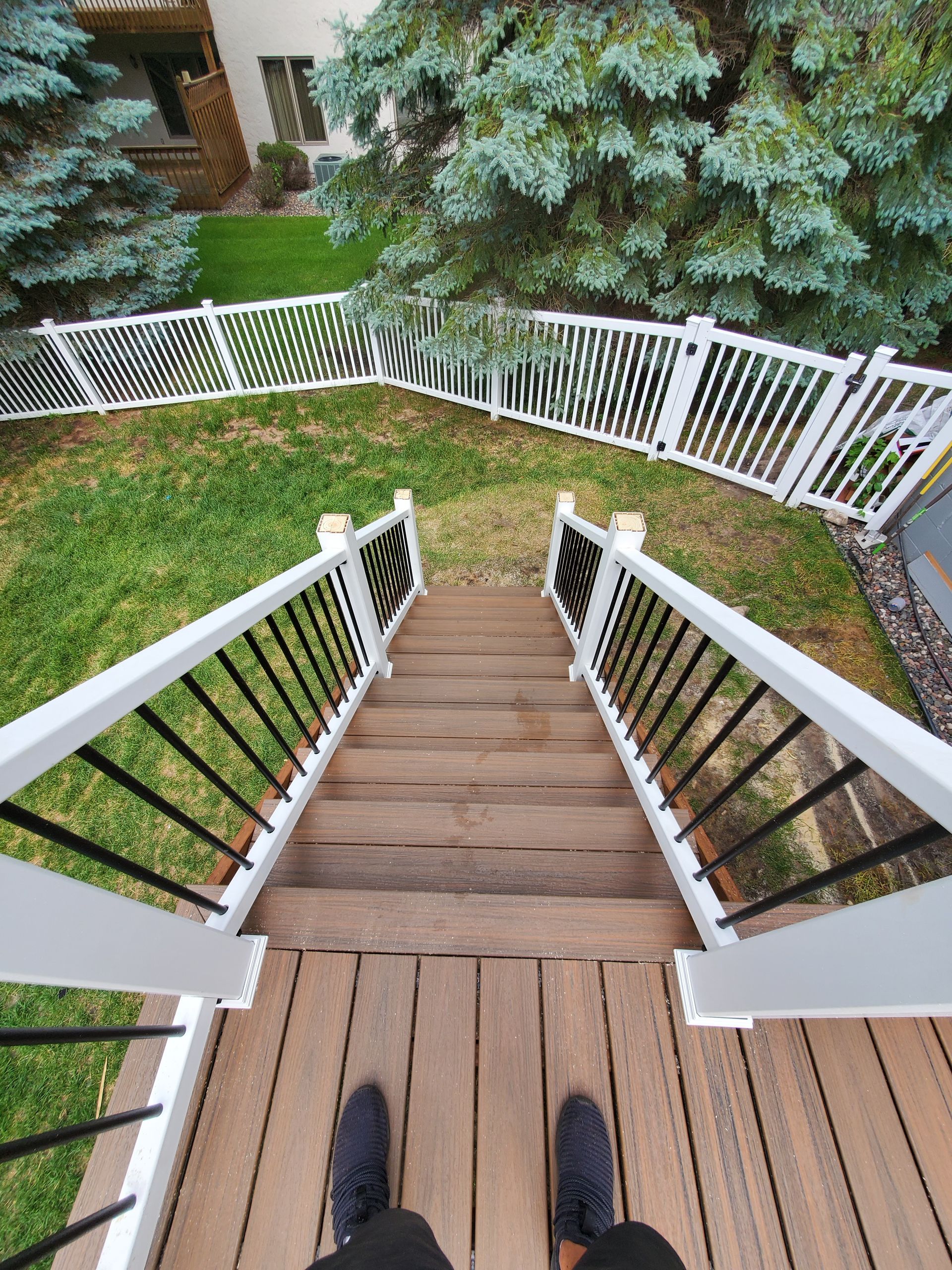 A person is standing on a wooden deck looking down the stairs.