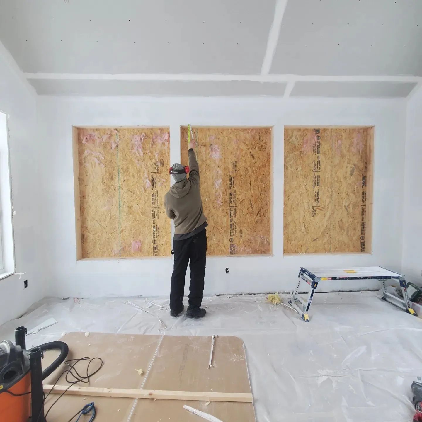 A man is measuring a wall with a tape measure