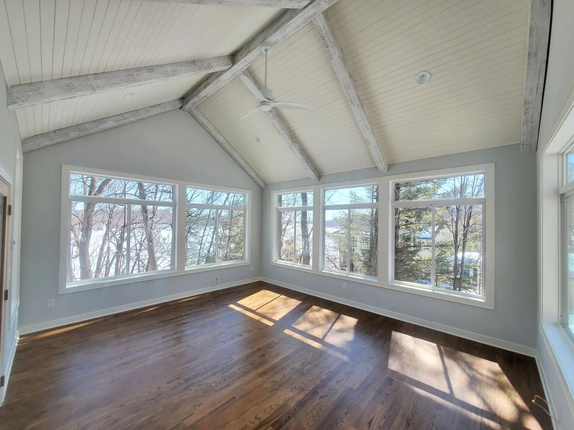 An empty room with a vaulted ceiling and lots of windows.