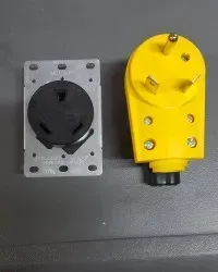 Two power plugs side by side: black plug on silver plate, yellow industrial plug on a gray surface