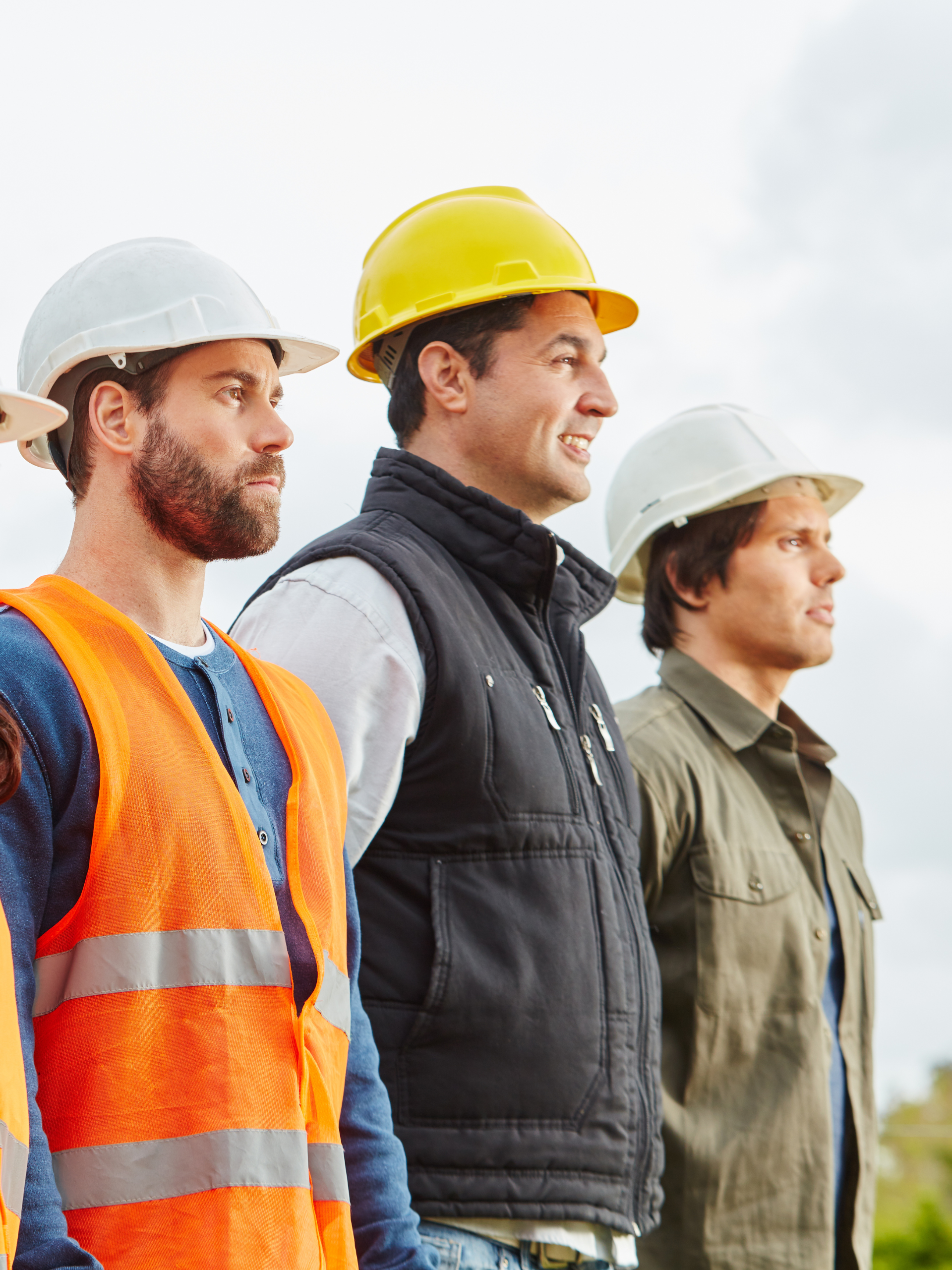 A group of construction workers wearing hard hats and vests are standing next to each other.