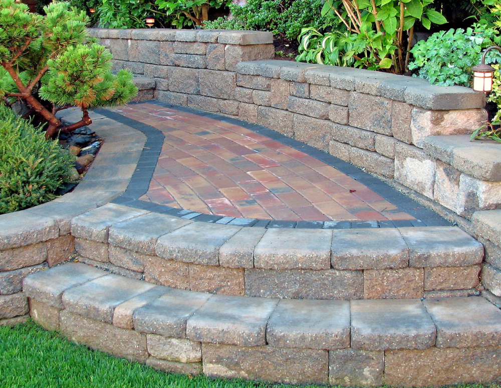 A stone wall with a brick walkway leading to it