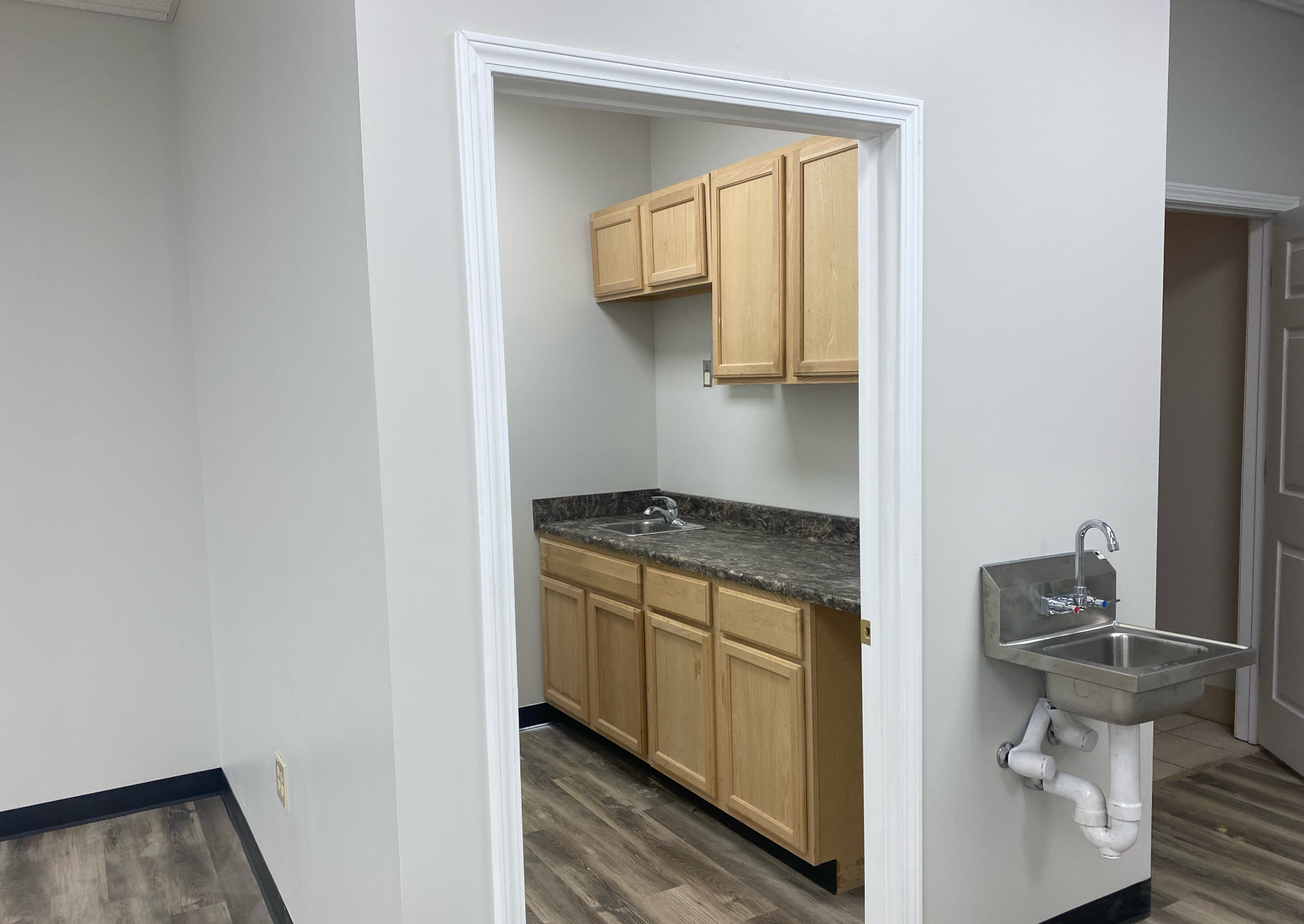 A kitchen with wooden cabinets , granite counter tops , and a sink remodeled by Hampton Construction & Development.