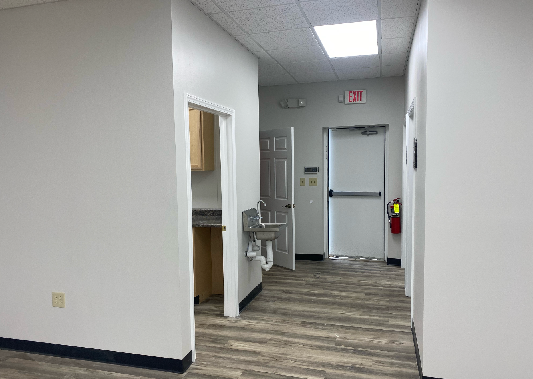 A hallway in a building with a sink and a fire extinguisher which was remodeled by Hampton Construction & Development.