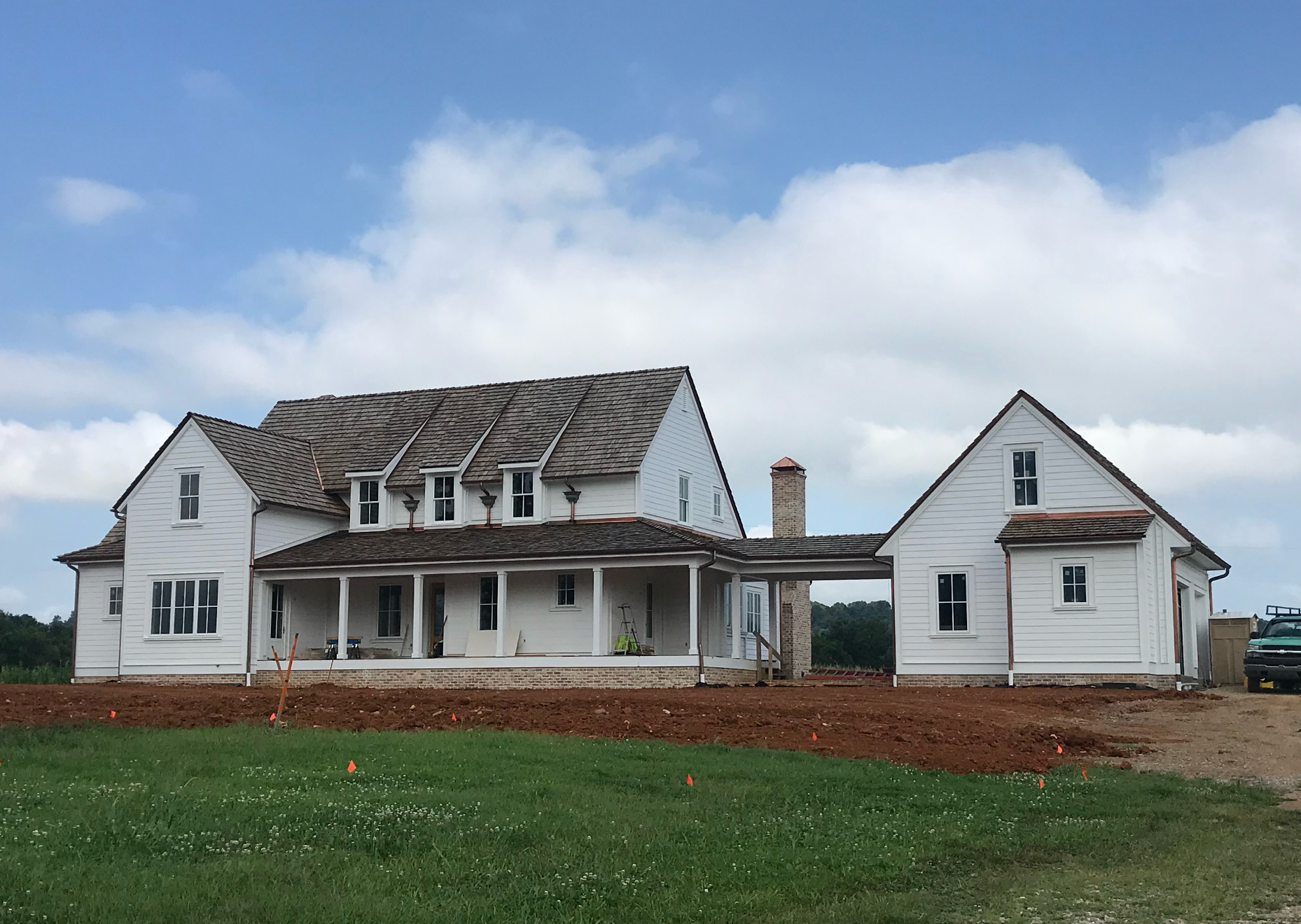 A large white house sits in the middle of a grassy field