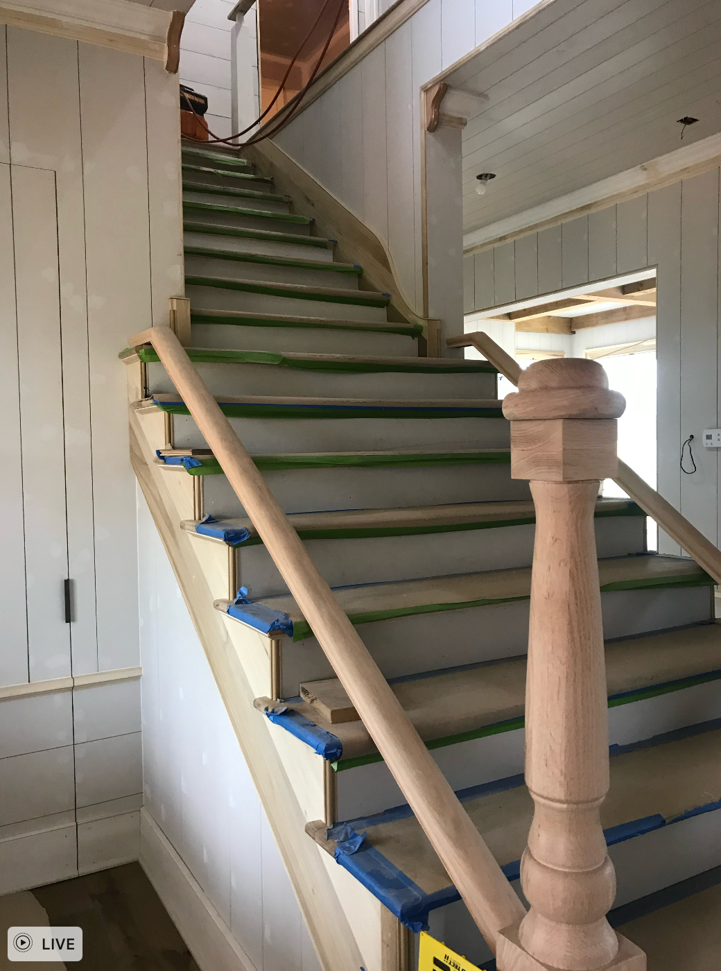 A staircase with a wooden railing is being painted in a house all built by Hampton Construction & Development.