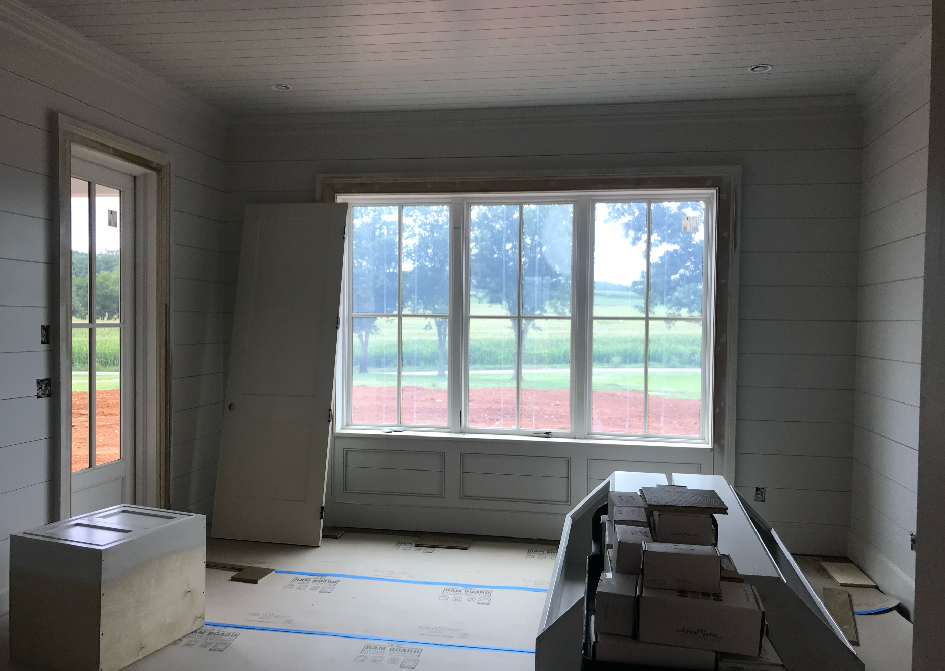 A room with a lot of windows and boxes on the floor