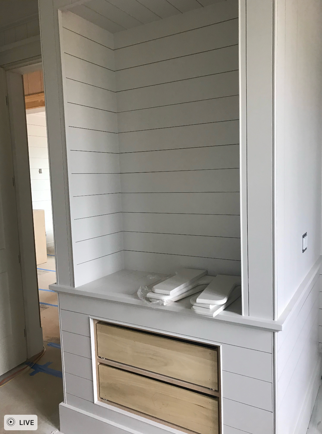 A white cabinet with wooden drawers and shelves in a room.