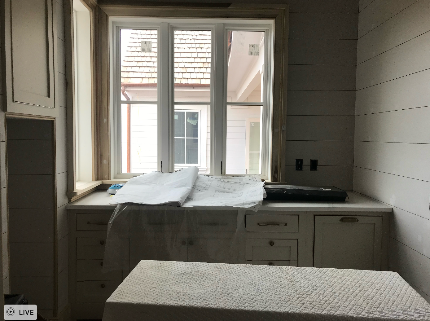 A kitchen with white cabinets and a large window.