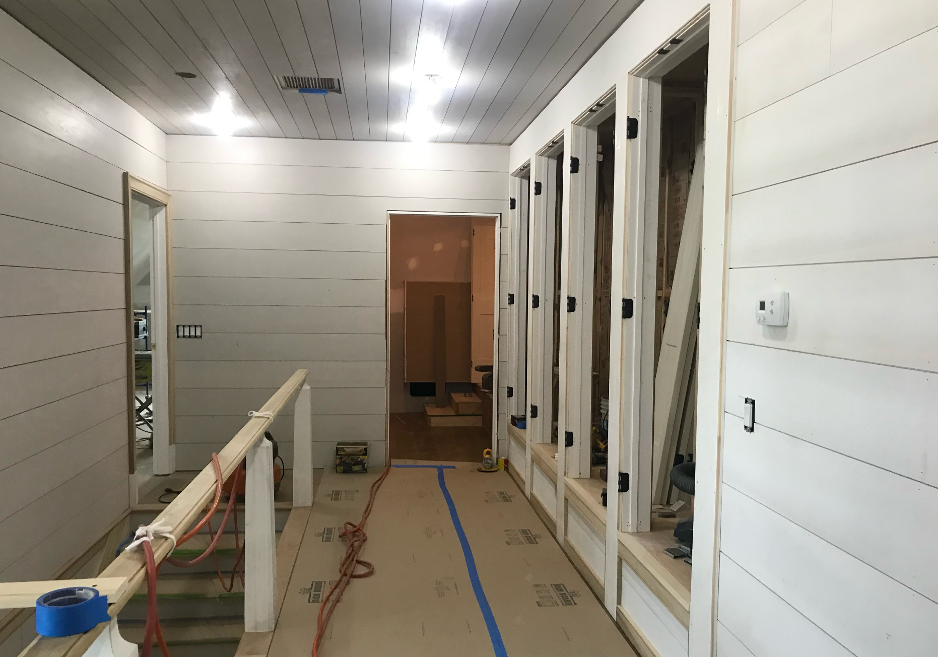 A long hallway with white walls and a blue tape on the floor.