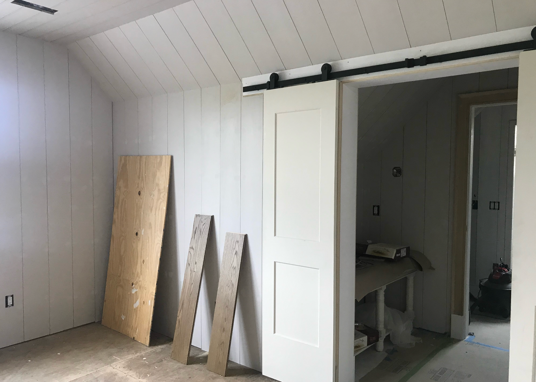 A room with a sliding barn door and wooden boards on the floor