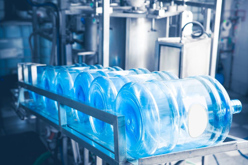 Botellas de agua de plástico azul en una cinta transportadora en una planta embotelladora.