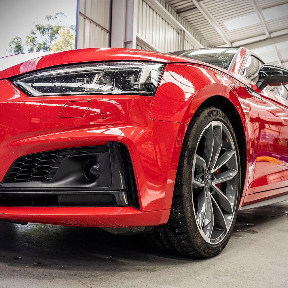 A red sports car is parked in a garage.