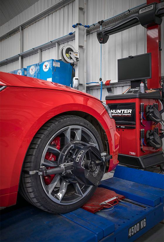 A red car is being adjusted by a machine in a garage.