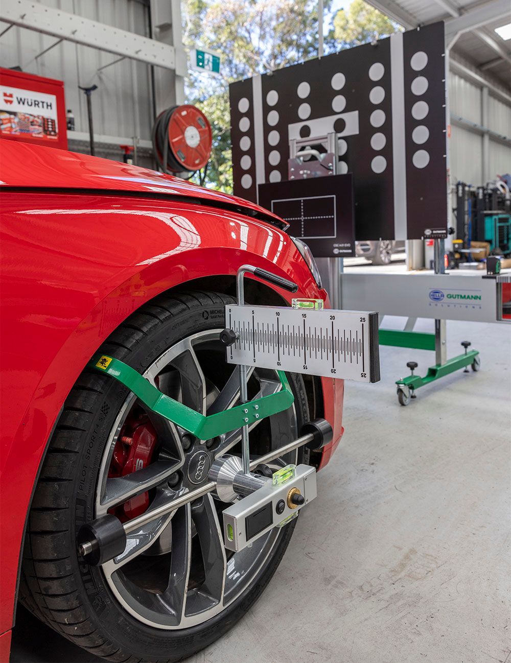 A red car is being aligned with a machine in a garage.