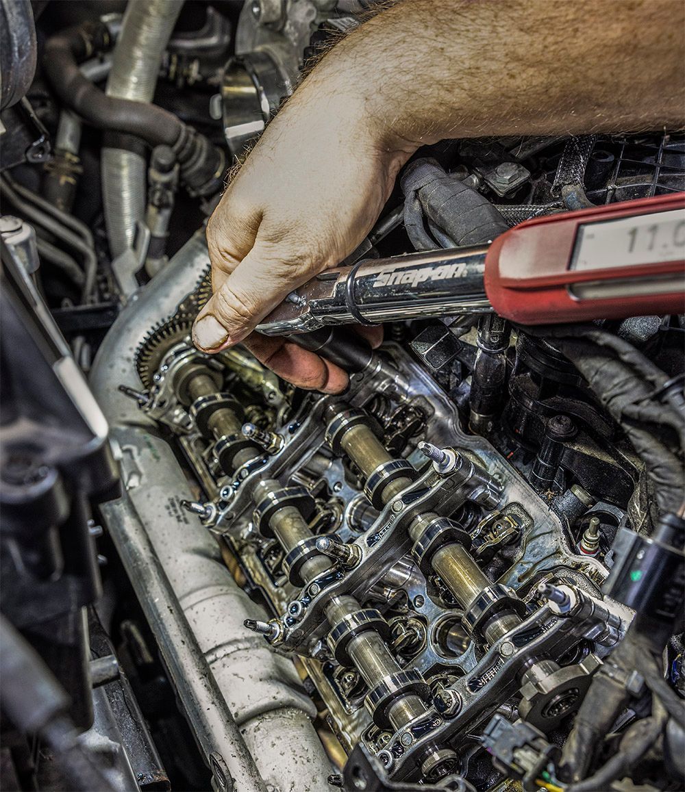 A man is working on a car engine with a wrench.