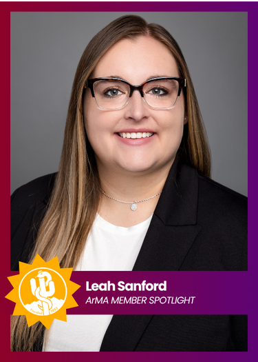 Headshot of Leah Sanford in glasses and black blazer, smiling on a purple alumni spotlight card.