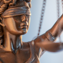 Close-up of a bronze Lady Justice statue with blindfold and raised arm, symbolizing law and fairness