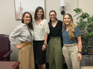 Four people standing together in an office, smiling at the camera.