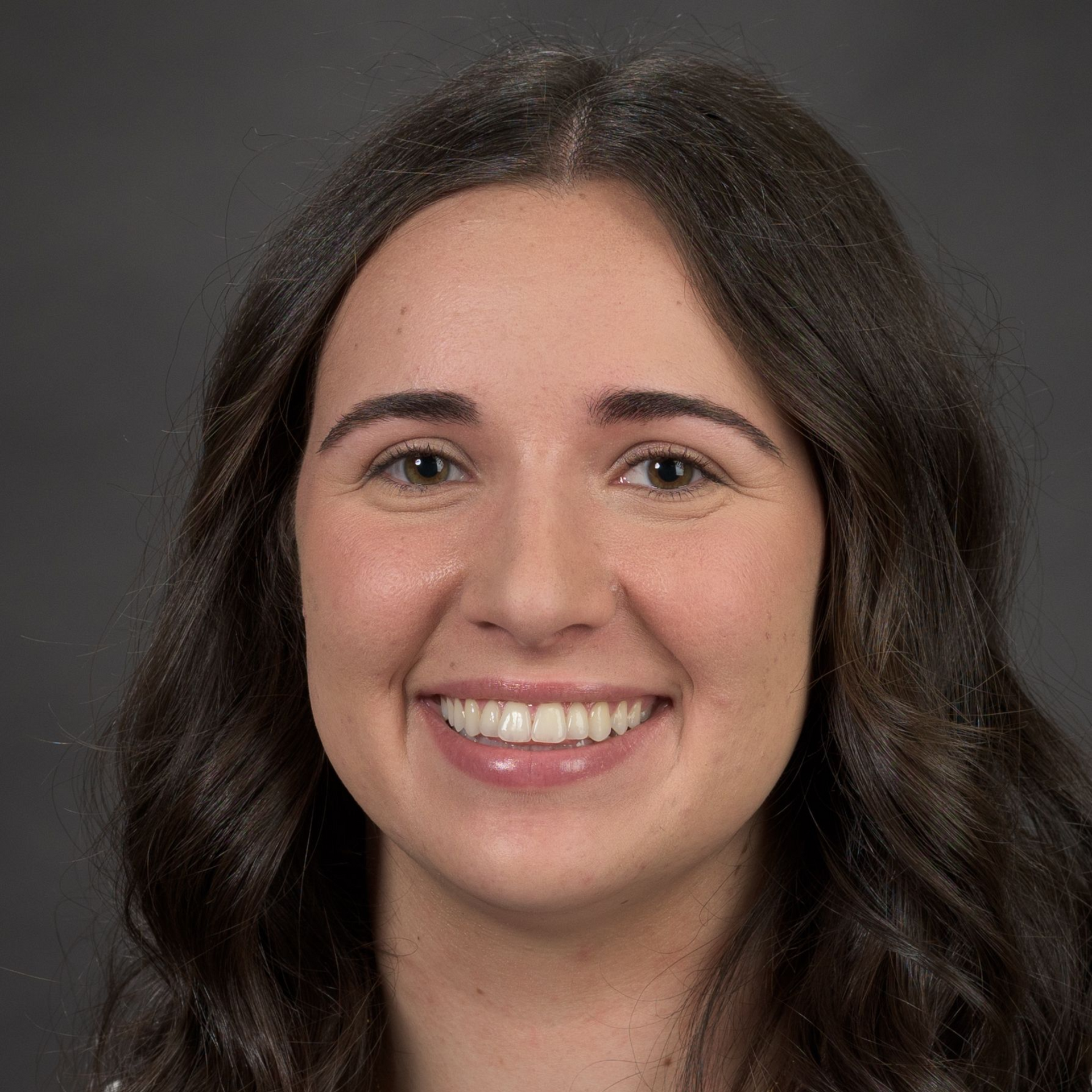 Studio headshot of a person in a blue blouse against a gray background