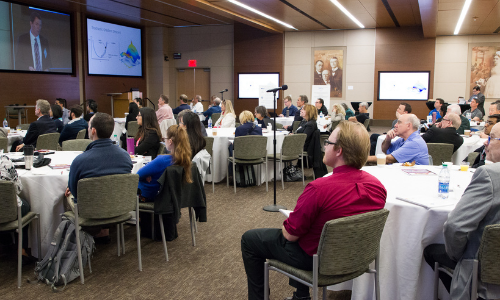 Conference room with seated attendees listening to a presentation at the front