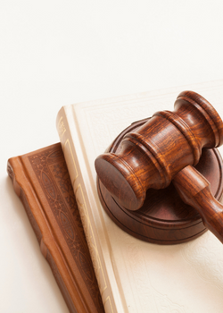 A wooden gavel rests on top a stack of decorative books.