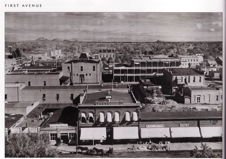 Aerial view of a dense city block with low buildings and mountains in the distance.