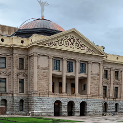 Historic stone building with a domed roof and decorative façade under a cloudy sky