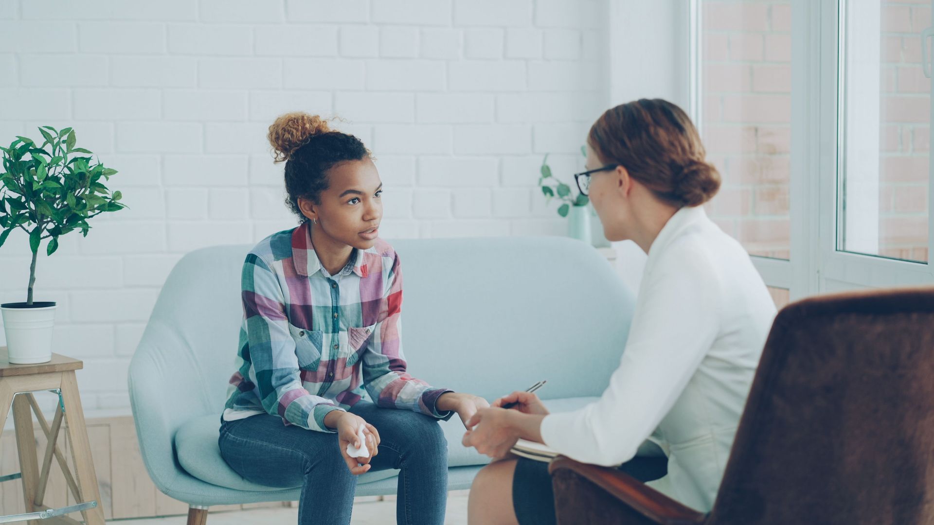 A clinician speaks to an adolescent girl in a professional setting.