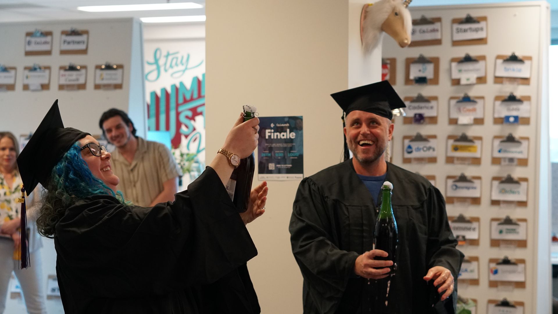 A woman is taking a picture of a man in a graduation cap and gown.