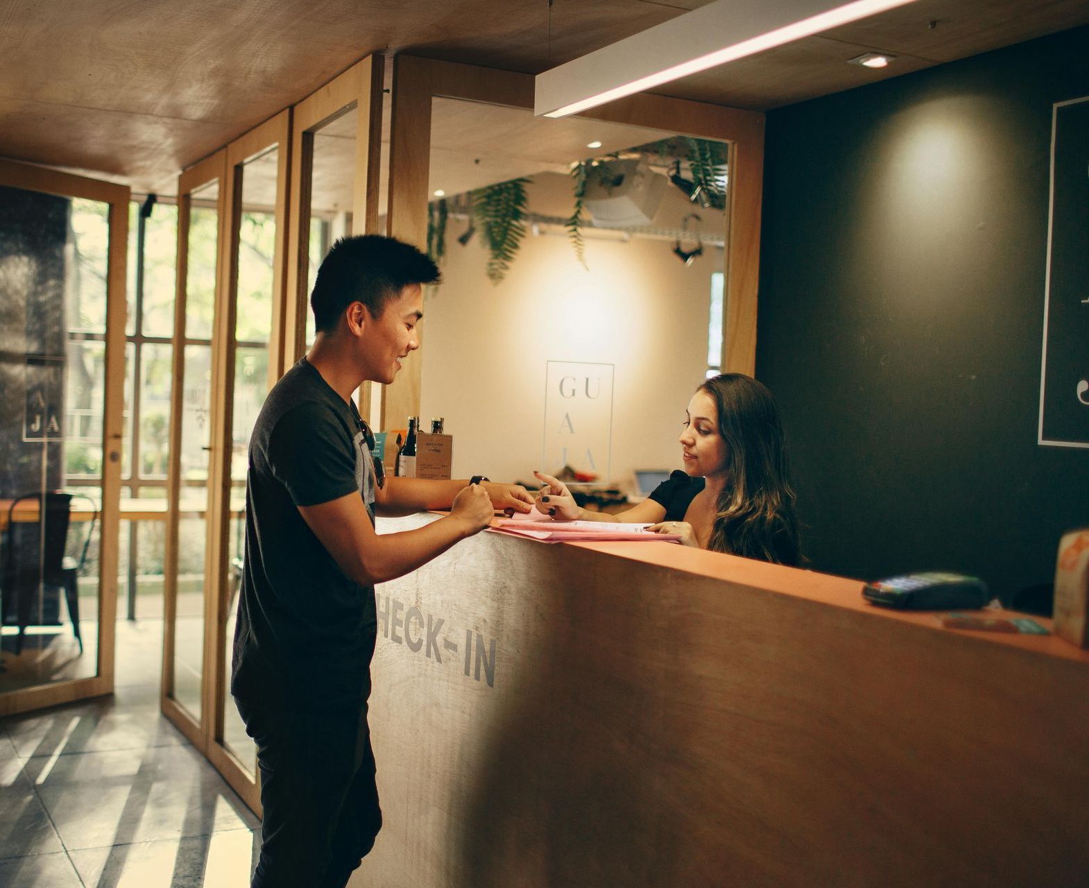 Person at a hotel reception desk handing over an item to a smiling clerk